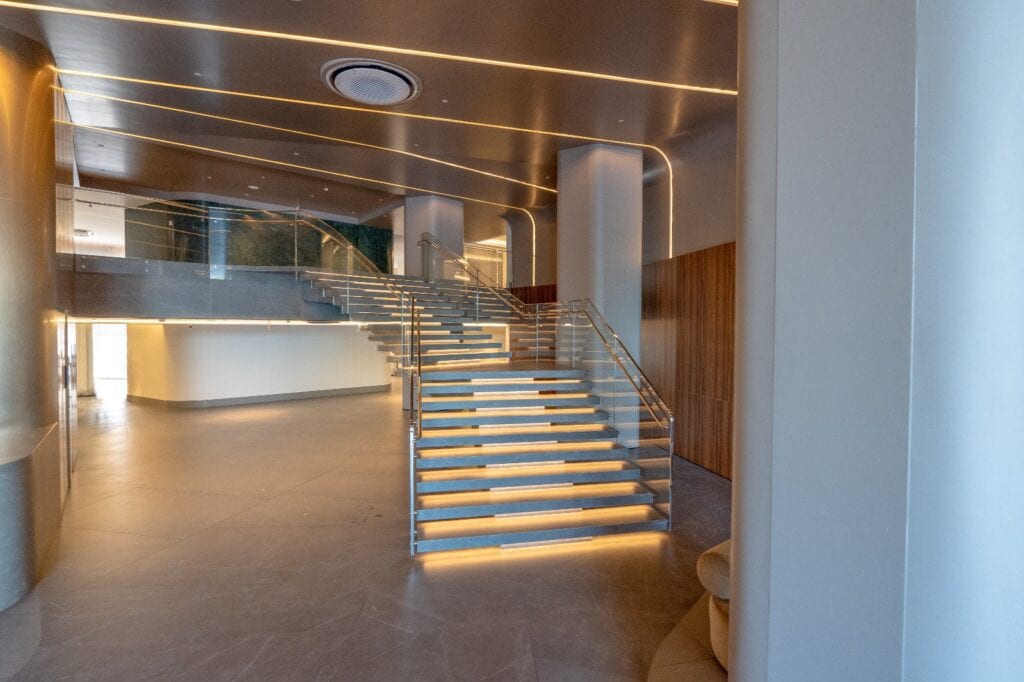 Escada do hall com corrimão em aço inox e guarda-corpo de vidro